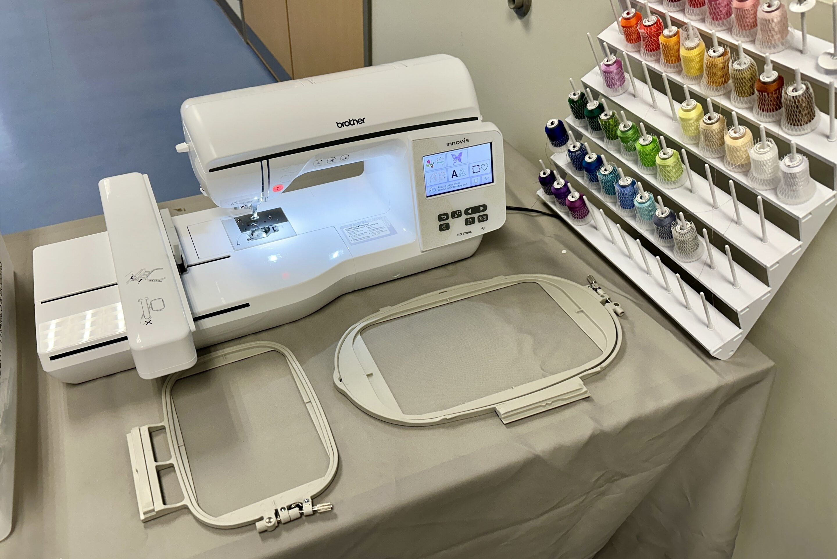 A photo of Ignite's new embroidery machine, two large hoops for the machine, and a selection of colorful embroidery thread.