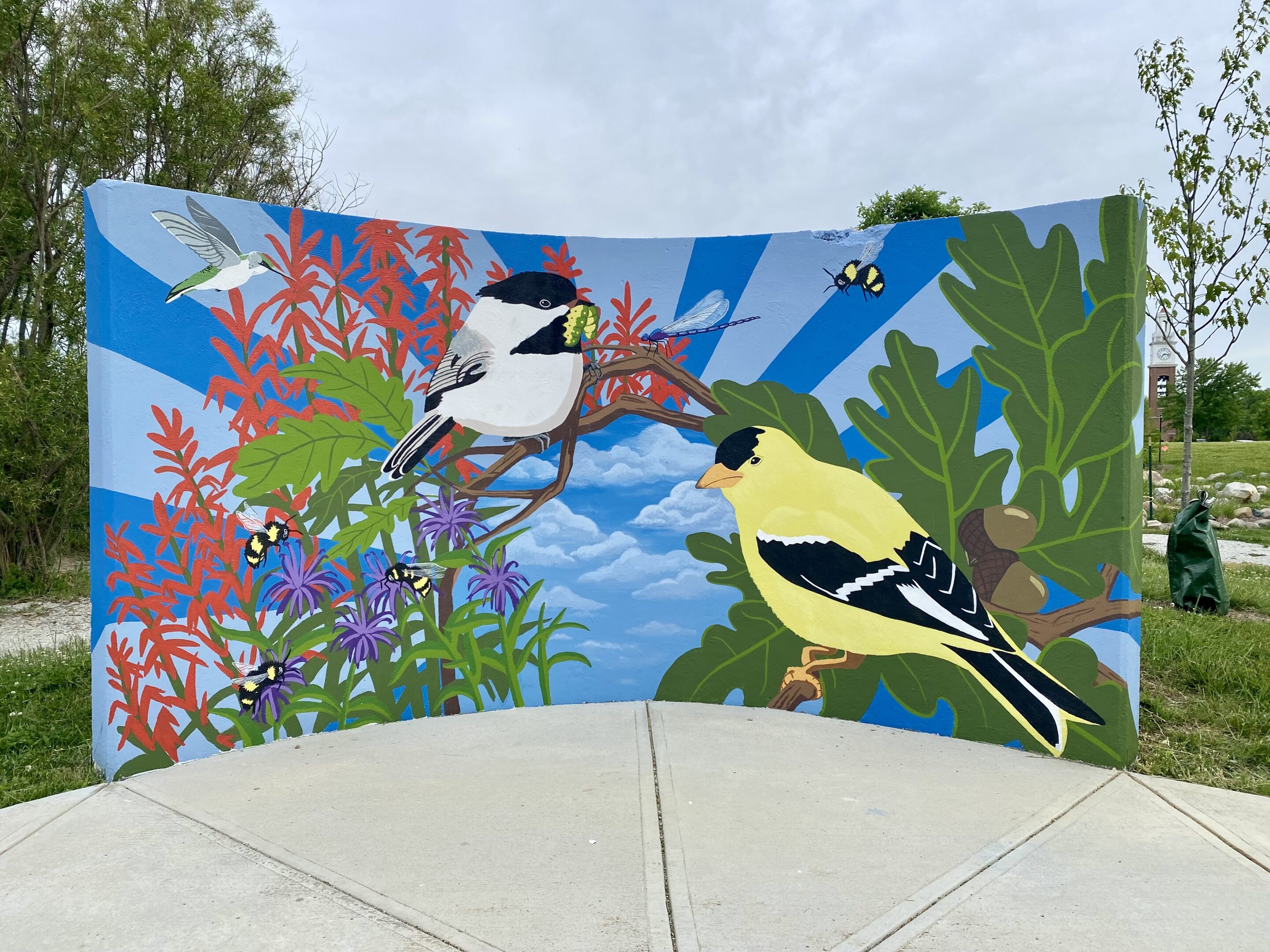 a mural of two birds with a leafy background