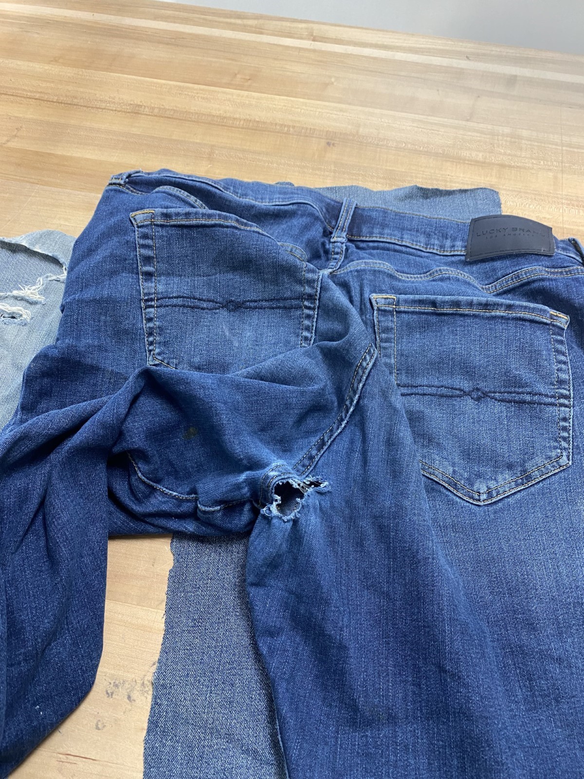 Another pair of blue jeans with a hole near the rear center seam.
