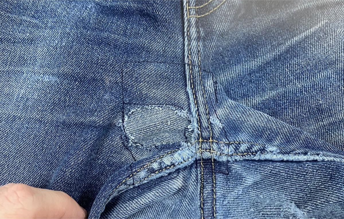 Exterior of Jeans at center seams where two squares of sewing thread is visible 