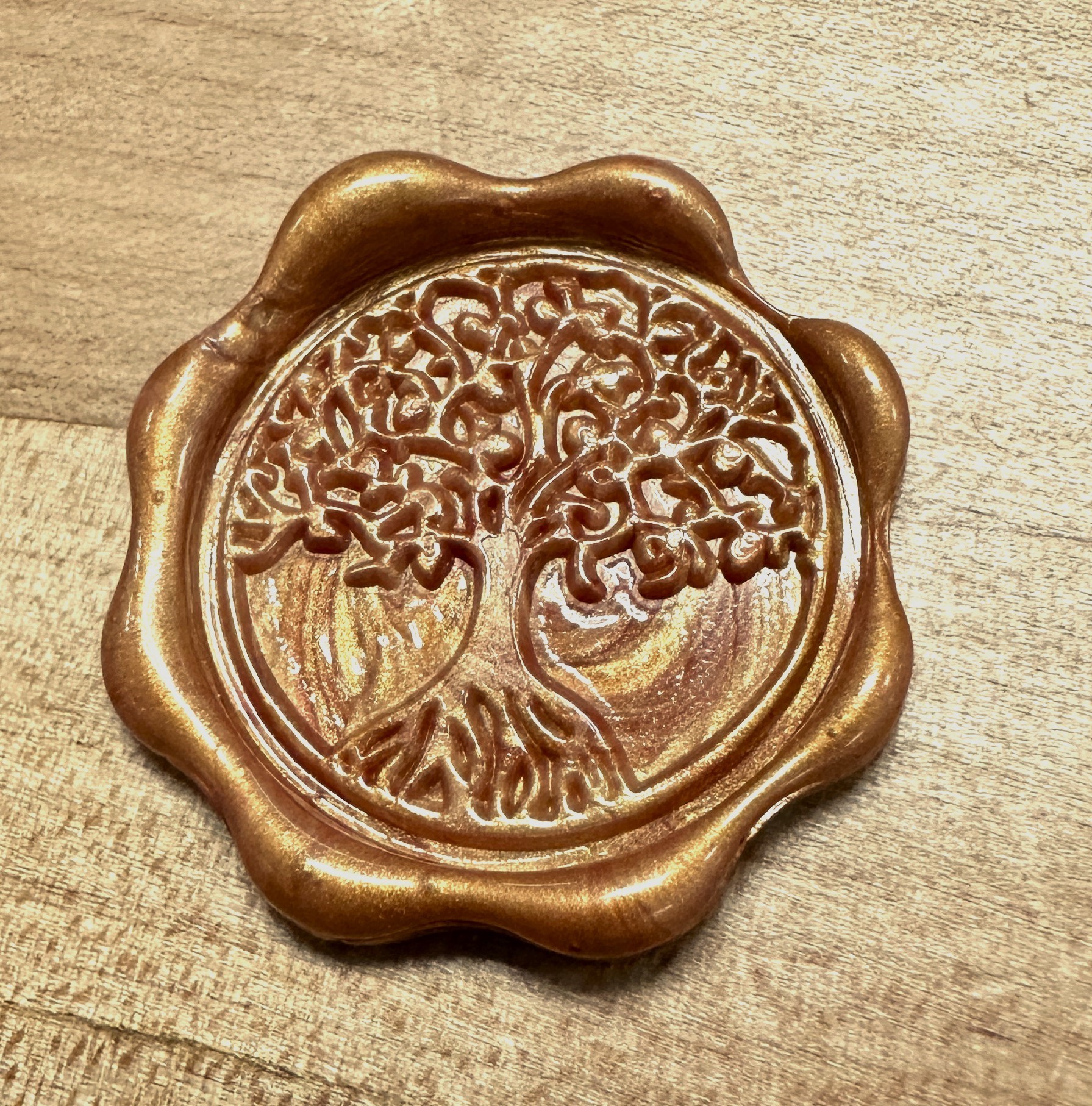 A close up of a completed wax stamp in the shape of a tree.