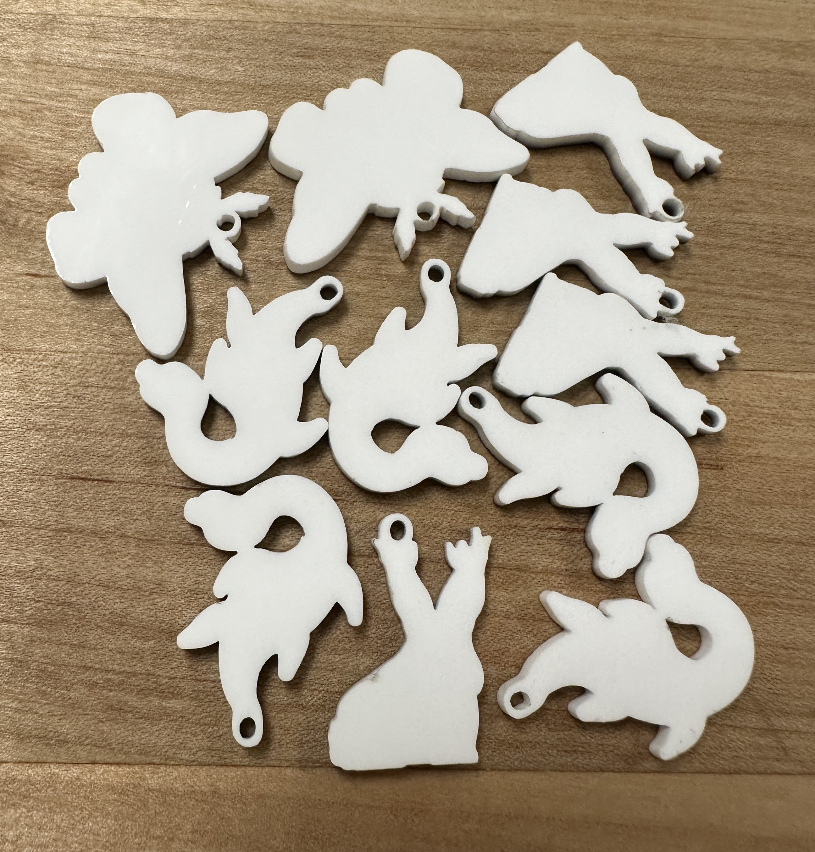10 solid white acrylic pieces cut into various shapes of cryptids.