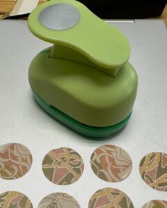 A 1-inch circle cutter next to some patterned paper circles 