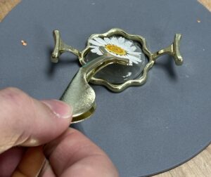 A dried flower being placed onto hot wax. 