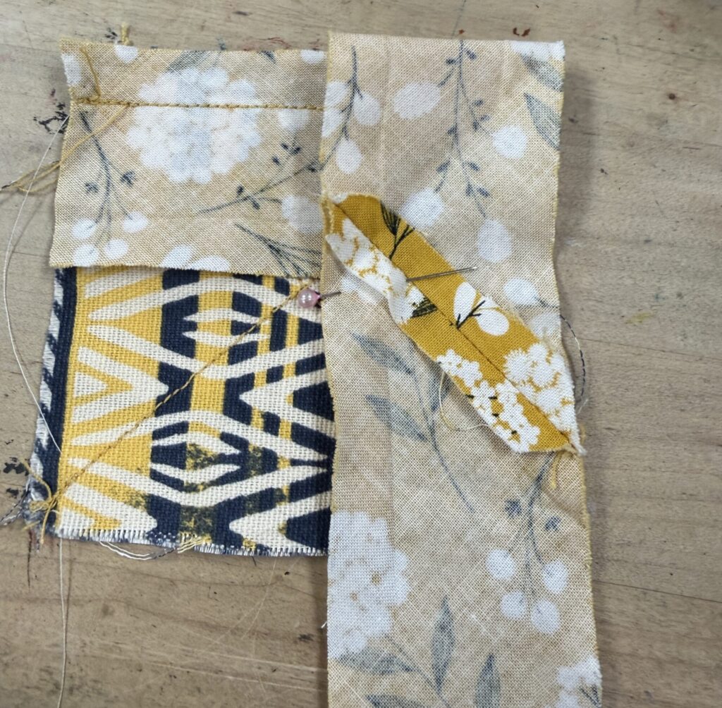 Bias tape folded back down to be perpendicular to the first seam. The patterned side of the tape is facing down. 