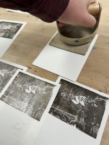 Using a barren to press the linoleum to make prints