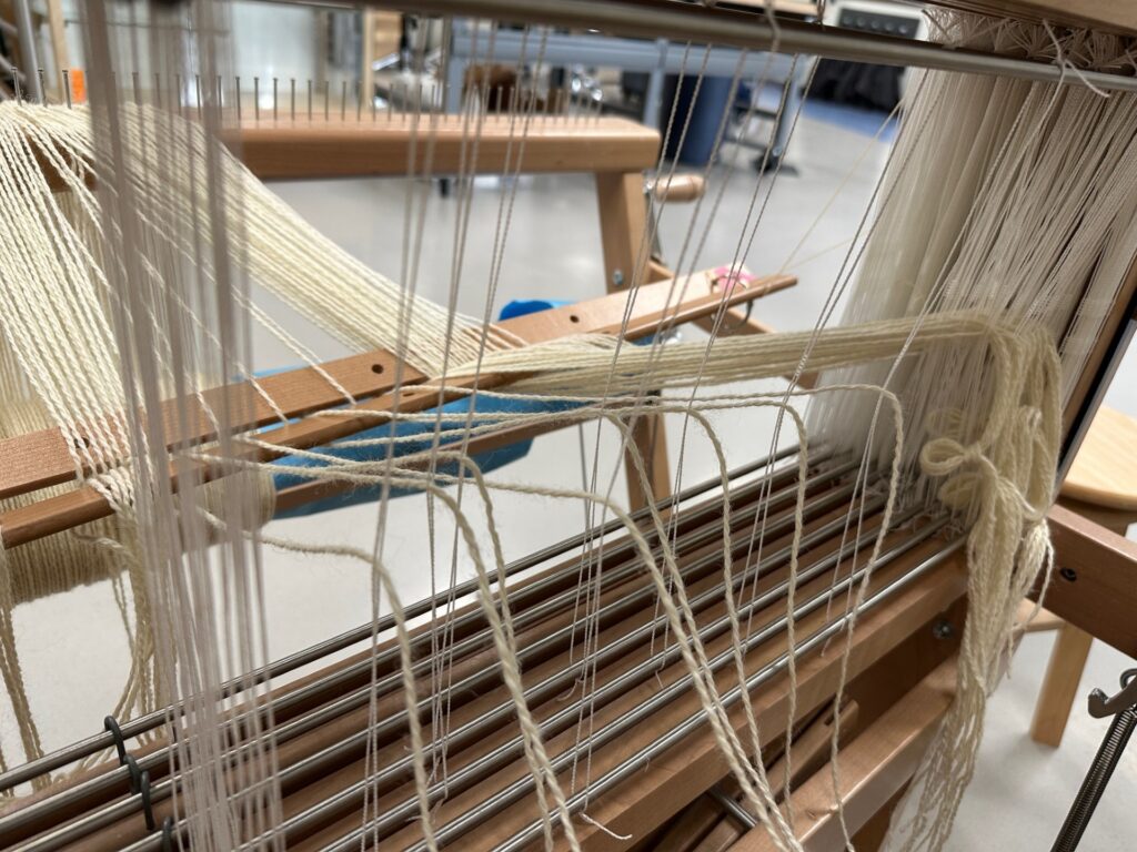 Yarn threads being strung through the heddles.