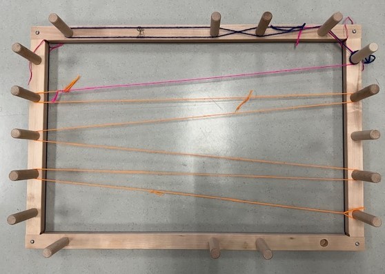 Photograph of warping board with one string of guide yarn tied on.