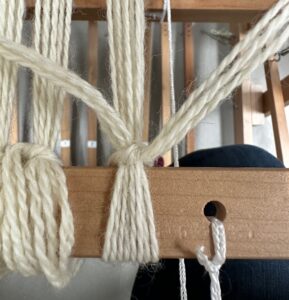 Group of yarn threads being tied to take up wheel.