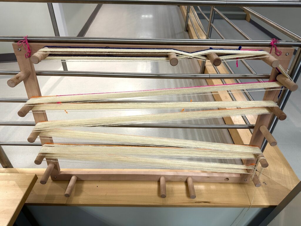 Warping board with white yarns added.