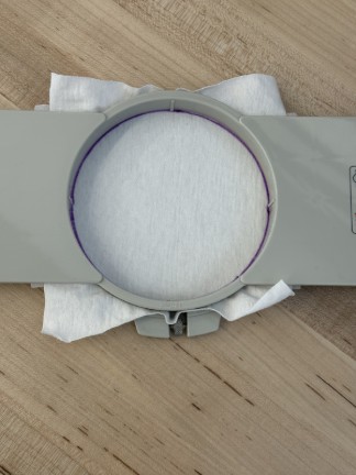 White fabric inside round embroidery frame.