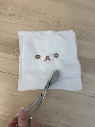 Stabilizer being cut from embroidered fabric.