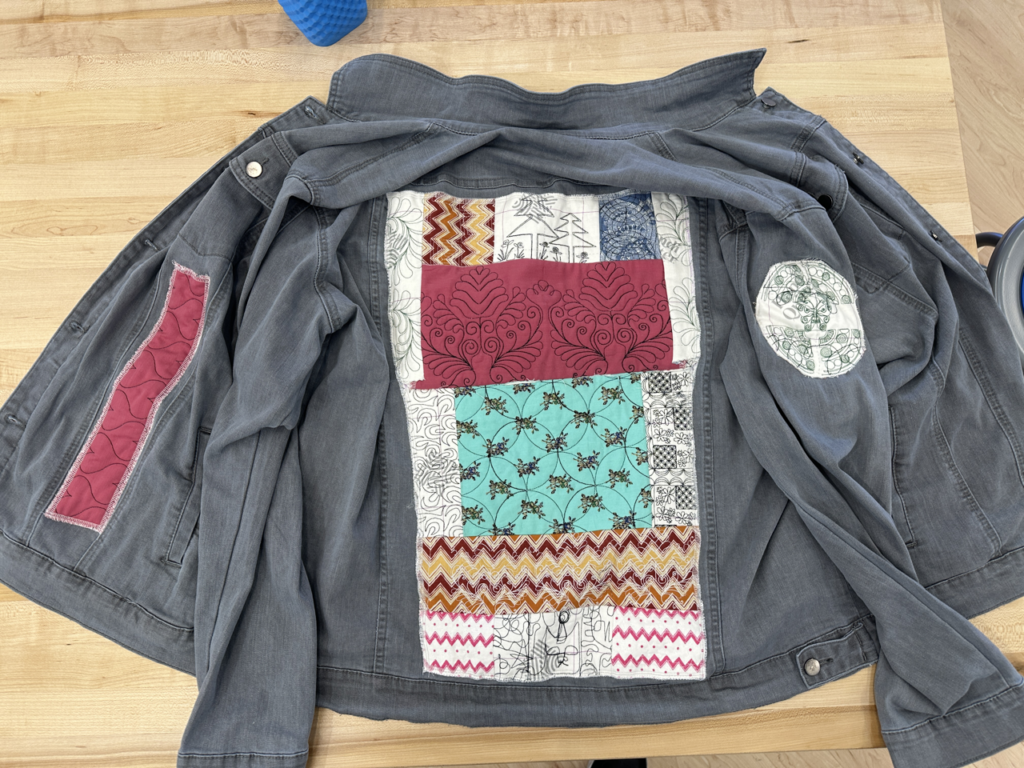 Gray jean jacket with patchwork fabric on back panel.